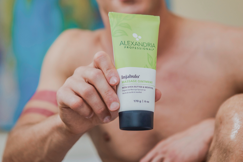 picture of green tube of Alexandria Professional's Injabulo massage ointment in the hands of a muscular man